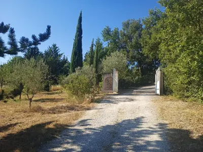 a gate on a dirt road next to trees at Chalet de Provence in Aix-en-Provence