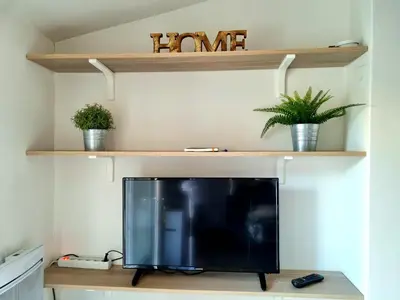 a television sitting on a table with shelves at Un balcon sur les toits d'Aix in Aix-en-Provence