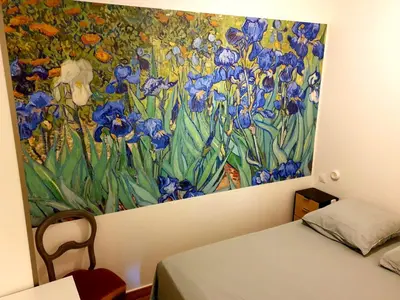 a painting of blue flowers on a wall next to a bed at Appartement à L'Isle-sur-la-Sorgue avec vue sur la ville in LʼIsle-sur-la-Sorgue