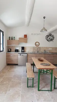 a kitchen with a wooden table and a green table and bench at le moulin in Crillon-le-Brave