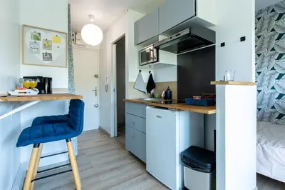 a small kitchen with blue cabinets and a blue bar stool at Studio cosy à proximité du centre ville in Aix-en-Provence
