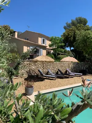 a pool with chairs and umbrellas in front of a house at Le Jardin sur la colline près du Golf in LʼIsle-sur-la-Sorgue