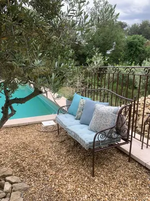 a couch sitting on a balcony next to a pool at Le Jardin sur la colline près du Golf in LʼIsle-sur-la-Sorgue