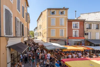 a crowd of people walking around a street with umbrellas at L'IRIS D OR - 3 Étoiles- 3ème étage in LʼIsle-sur-la-Sorgue