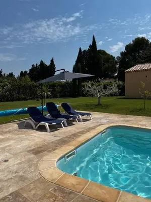 a swimming pool with two chairs and an umbrella at Magnifique maisonnette Dépendance avec Piscine in Châteaurenard