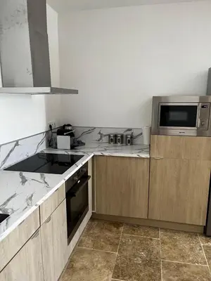 a kitchen with wooden cabinets and a microwave at Magnifique maisonnette Dépendance avec Piscine in Châteaurenard