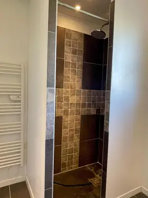 a shower in a bathroom with a tiled wall at La Remise de Guytou et Spa in Cheval-Blanc