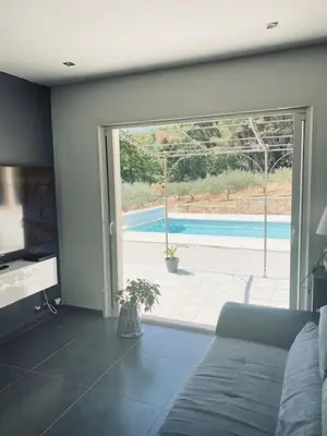 a living room with a couch and a view of a pool at Jolie maison de 110 m 2, pour 6 personnes, au calme, avec piscine in Les Cordiers