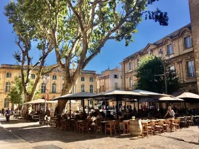 a group of tables and chairs with umbrellas in front of a building at Petit cocoon Aixois in Aix-en-Provence