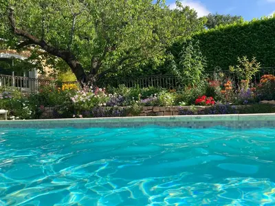 a swimming pool in a garden with flowers at Les Hauts d'Eyragues gîte Aigue Marine Meublé classé 4 étoiles in Eyragues