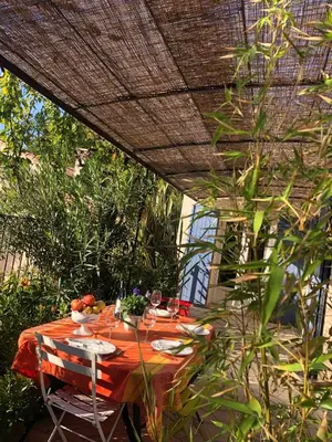 a table with a red table cloth on a patio at Les Hauts d'Eyragues gite Rêverie Meublé classé 4 étoiles in Eyragues