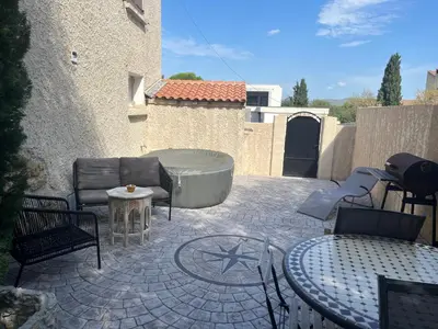 a patio with a tub and chairs and a table at Charmant logement avec un extérieur et un jacuzzi in Lançon-Provence