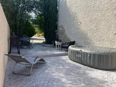 a patio with a chair and a tub next to a building at Charmant logement avec un extérieur et un jacuzzi in Lançon-Provence