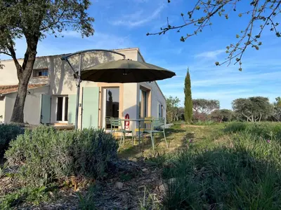 a house with an umbrella in front of it at Paisible gîte moderne avec vue sur le Luberon in La Motte-dʼAigues