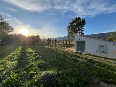 a house in a field with the sunset in the background at Paisible gîte moderne avec vue sur le Luberon in La Motte-dʼAigues