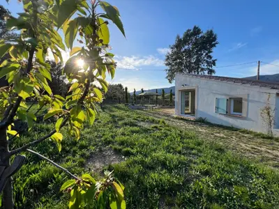 a small house in a field next to a building at Paisible gîte moderne avec vue sur le Luberon in La Motte-dʼAigues