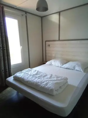 a large bed with white sheets and a window at Mes deux Gîtes de l'Ocre in Villars