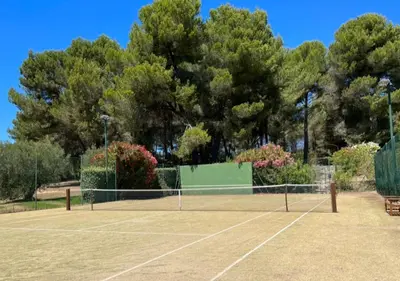 a tennis court with a net and some trees at La Villa La Source à Aix en Provence in Aix-en-Provence