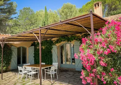 a patio with a table and chairs and pink flowers at La Villa La Source à Aix en Provence in Aix-en-Provence