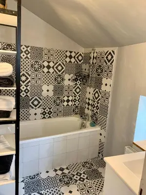 a bathroom with a black and white tiled wall at Au cœur de l’Isle sur sorgue in LʼIsle-sur-la-Sorgue
