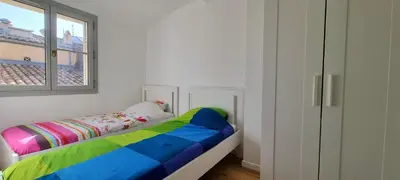 a bedroom with a rainbow bed and a window at Les toits de Mignet in Aix-en-Provence