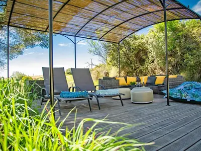 a patio with chairs and a couch under an umbrella at Villa Cantirane in Saint-Pierre-de-Vassols