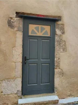 a green door on the side of a stone building at Maison de ville au coeur du centre historique, parking gratuit in Apt