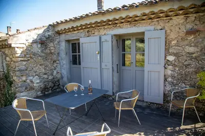 a table and chairs on a patio in front of a stone building at Domaine Les Perpetus in La Tour-dʼAigues