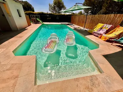 a swimming pool with two chairs in the water at Anse Coco Luberon - Au calme, gite en Provence avec piscine partagée et parking in Pertuis