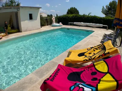 a swimming pool with two lawn chairs next to it at Anse Coco Luberon - Au calme, gite en Provence avec piscine partagée et parking in Pertuis