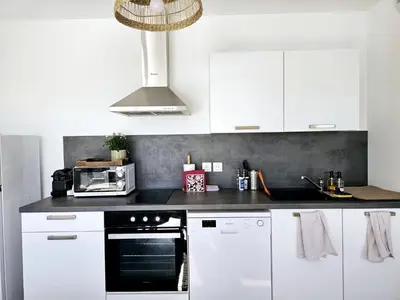 a kitchen with white cabinets and a black oven at Lakeside Provence - Appartement classé 4 étoiles, Vue sur le lac de Monteux, Parking sous-sol, double clim in Monteux