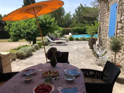a table with an umbrella and a bowl of fruit on it at very pleasant provençal mas, typical to the region, with heated pool in saint remy de provence - 9 people in Saint-Rémy-de-Provence