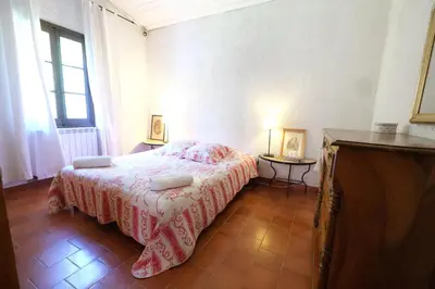 a bedroom with a bed with a red and white blanket at very pleasant provençal mas, typical to the region, with heated pool in saint remy de provence - 9 people in Saint-Rémy-de-Provence