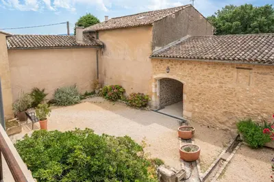 an outdoor courtyard of a building with potted plants at Domaine Mas Côté Cour in Maubec