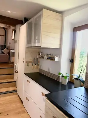 a kitchen with white cabinets and a black counter top at Maisonnette atypique cadarache-iter in Saint-Paul-lez-Durance