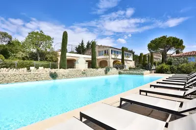 a swimming pool with lounge chairs in front of a house at Le Bastidon de Guillemette in Gordes