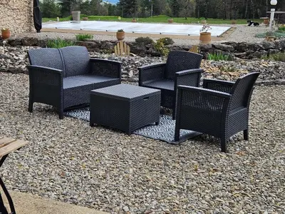 four wicker chairs and a table on a gravel patio at Gîte Le Refuge in Monieux