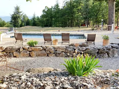 a group of chairs sitting next to a rock wall at Gîte Le Refuge in Monieux