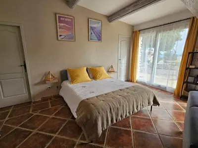 a bedroom with a bed and a large window at Gîte Le Refuge in Monieux