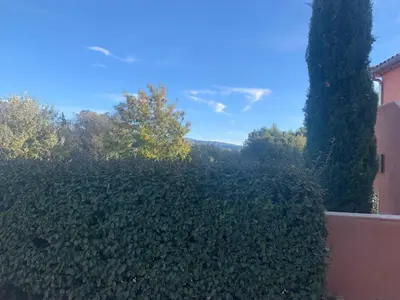 a hedge in front of a building with trees at la pinède in Roussillon
