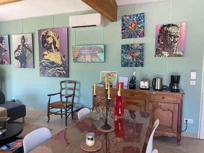 a dining room with a table and paintings on the wall at lagalerie84 in Saint-Saturnin-les-Apt