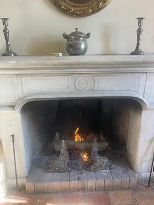 a stone fireplace with a fire in it at Suite le Quervalat dans magnifique bastide 18eme in Aix-en-Provence