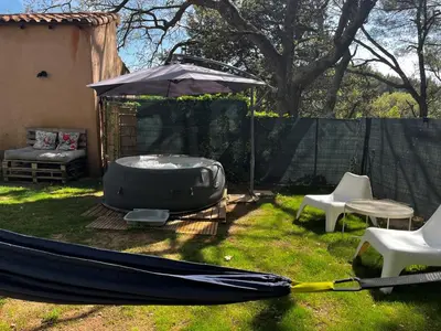 a hammock and an umbrella in a yard at Aix-en-Provence, Maison provençale au calme de la campagne avec Jacuzzi in Aix-en-Provence