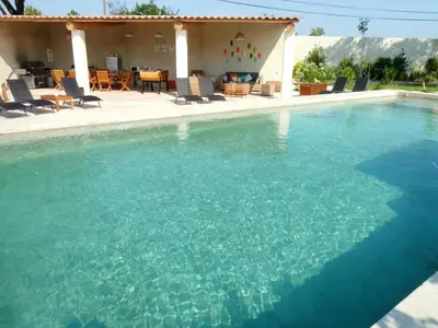 a large swimming pool with blue water in front of a house at Maison de 6 chambres avec piscine privée, jardin aménagé et wifi à Pernes-les-Fontaines in Pernes-les-Fontaines