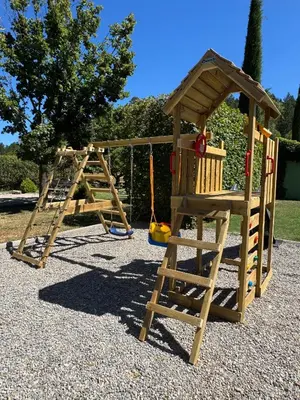a wooden playground with a ladder and a swing at Gîte Le Tramontane Meublé de tourisme 4 étoiles Le Moulin de Prédelles in Reillanne
