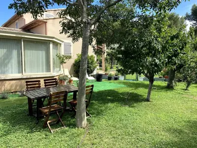 a wooden table and chairs in a yard at Les Lauriers en Lubéron in Cheval-Blanc