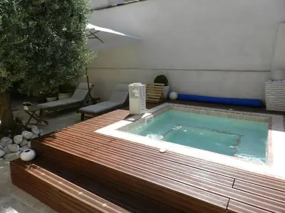a hot tub sitting on a deck next to a patio at Le Maset des Aires avec vue sur le Luberon et son jacuzzi extérieur disponible de juin à mi-septembre in Maubec