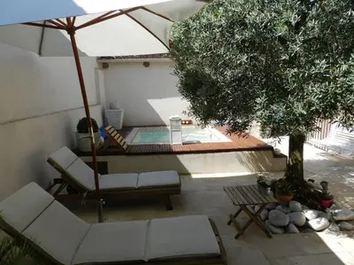 a patio with two chairs and an umbrella and a pool at Le Maset des Aires avec vue sur le Luberon et son jacuzzi extérieur disponible de juin à mi-septembre in Maubec