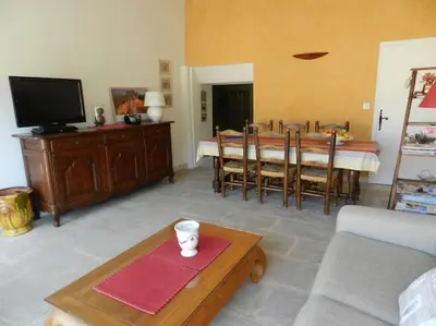 a living room with a table and a tv at Le Maset des Aires avec vue sur le Luberon et son jacuzzi extérieur disponible de juin à mi-septembre in Maubec