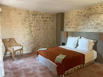 a bedroom with a bed and a chair in a room at La Planette in Venasque